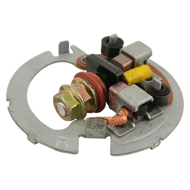 Close-up of a metal Mitsuba Polaris starter brush assembly with copper elements and spring contacts on a white background